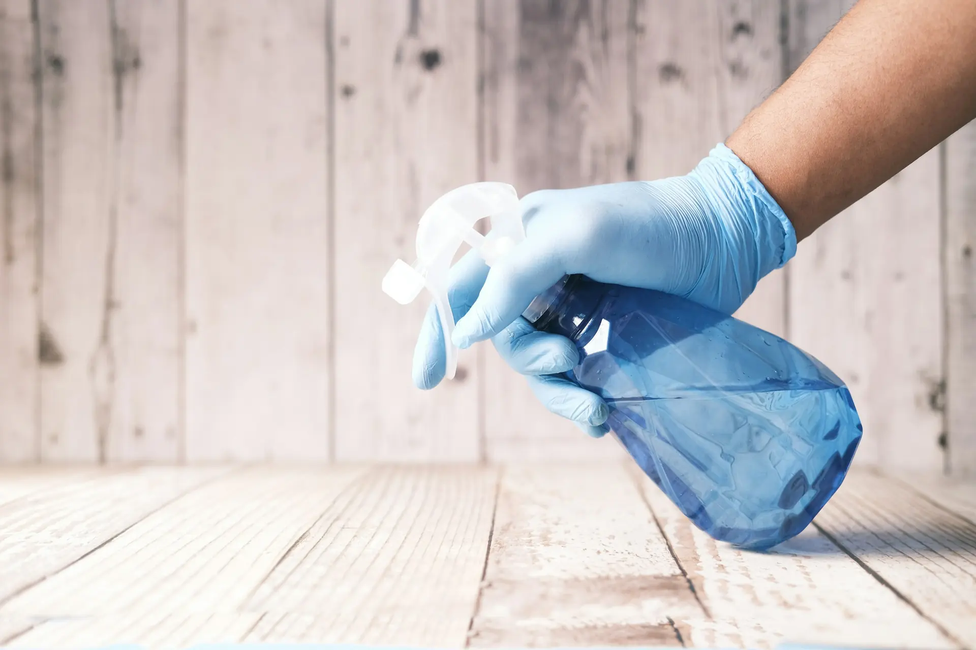 Hand mit Schutzhandschuh und Sprühflasche bei der Desinfektion - Spezialreinigung von Künzler