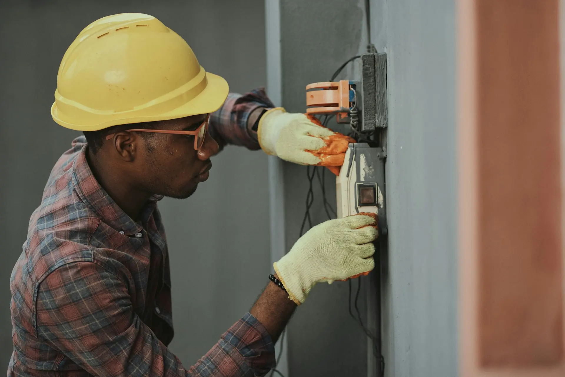 Techniker mit Schutzhelm prüft eine elektrische Anlage - technisches Facility Management von Künzler