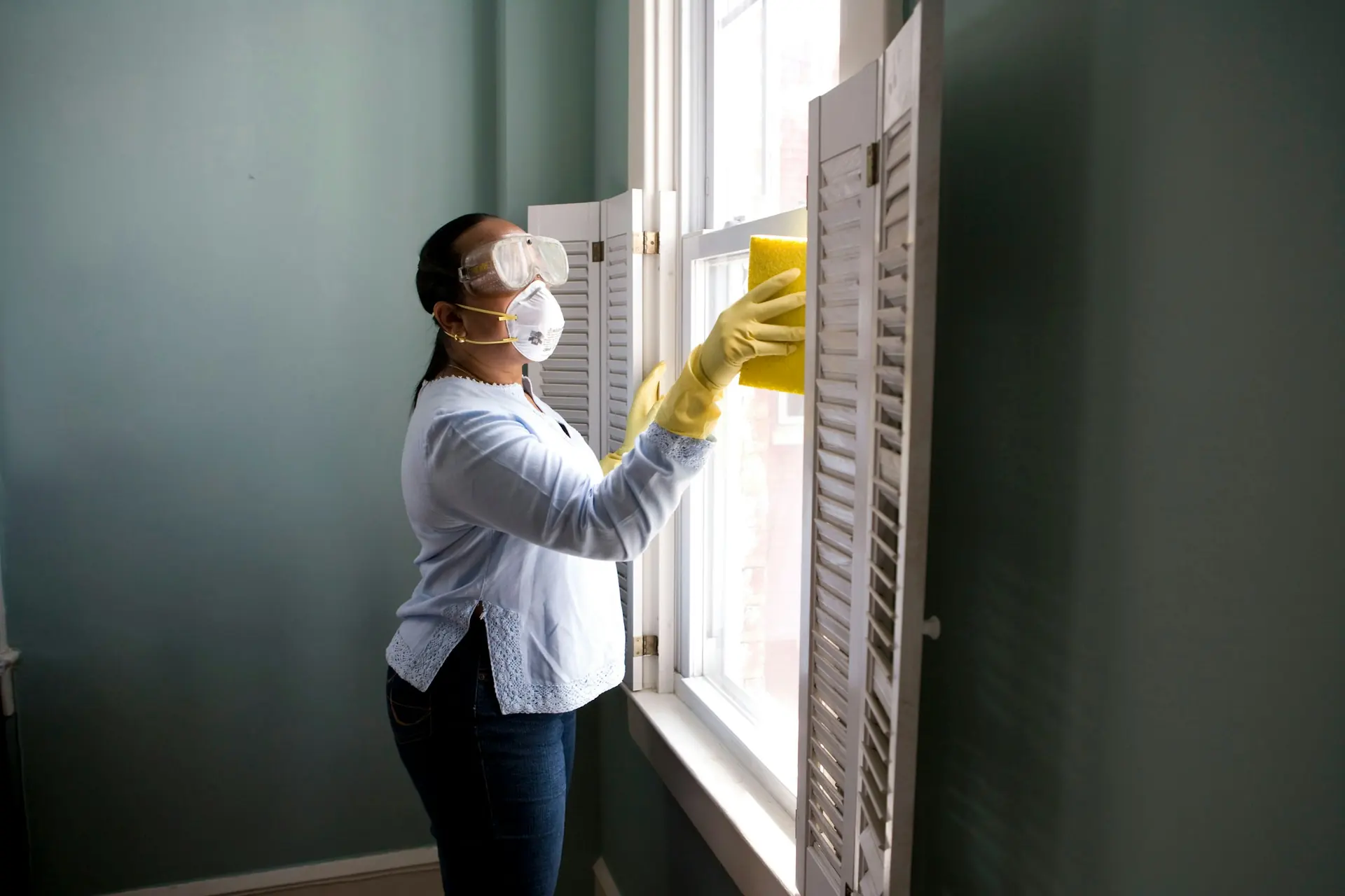 Reinigungskraft mit Handschuhen reinigt ein Fenster - Unterhaltsreinigung von Künzler Facility Management
